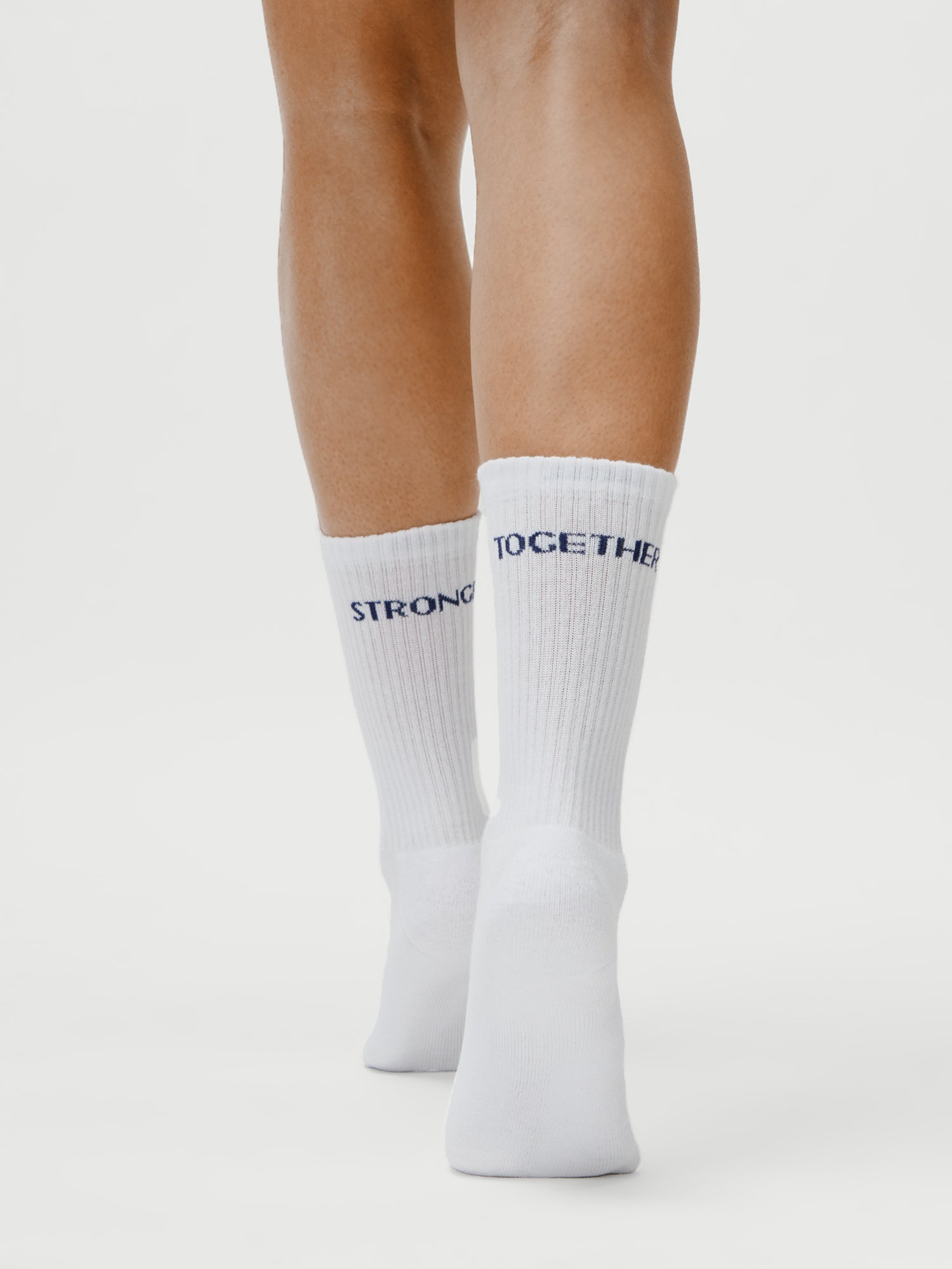 Eine Person (1,73m, Größe 36) trägt LeGer x Oh April - Sue Socks Stronger by LeGer by Lena Gercke - weiße gerippte Socken mit "STRONGER" auf der linken und "TOGETHER" auf der rechten Seite - vor einem weißen Hintergrund.