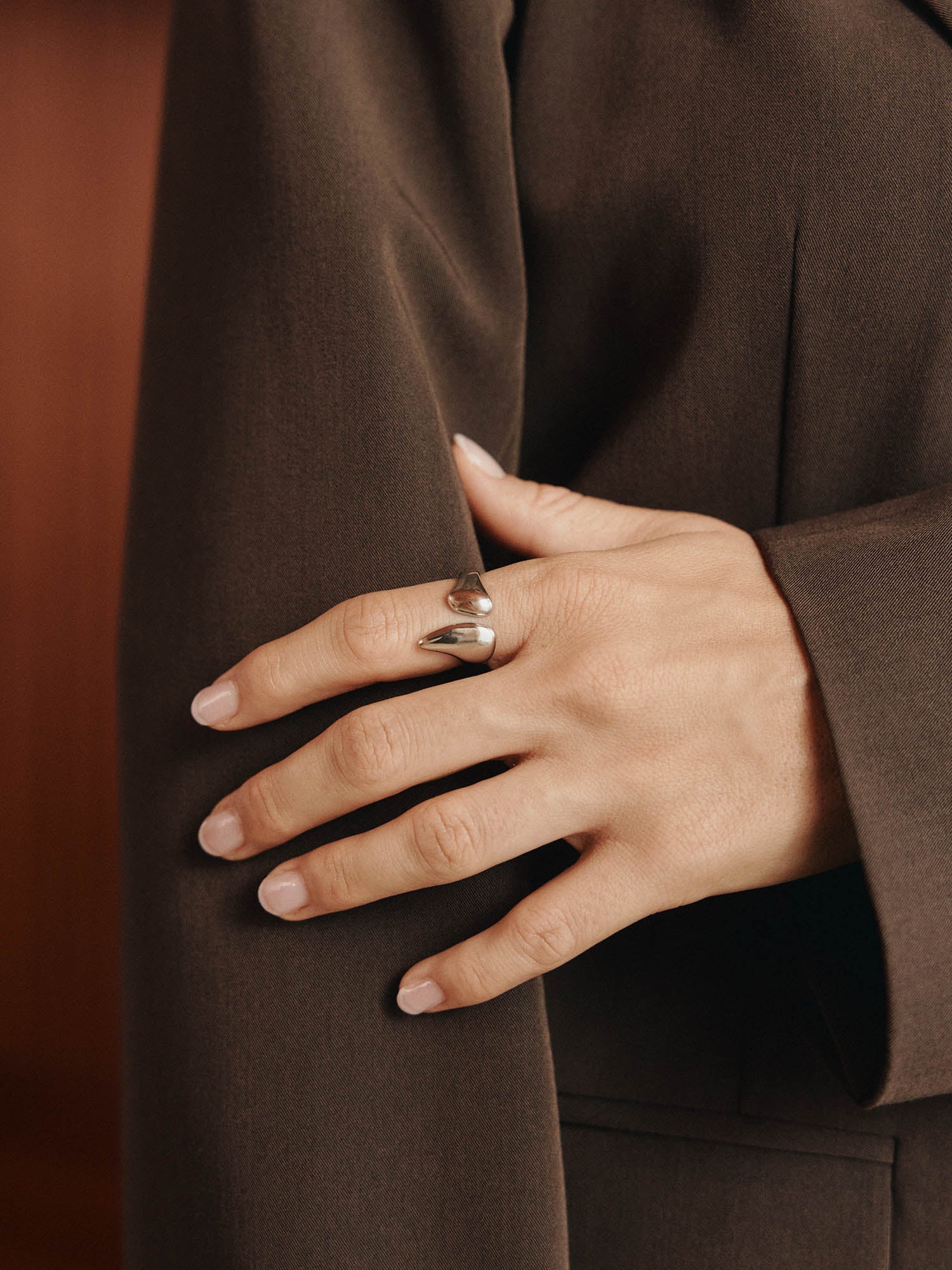 Eine Nahaufnahme einer manikürten Hand auf einem braunen Blazerärmel, die den LeGer x Purelei - Freedom Ring by LeGer by Lena Gercke trägt - einen klobigen Silberring mit einem einzigartigen, offenen Design.