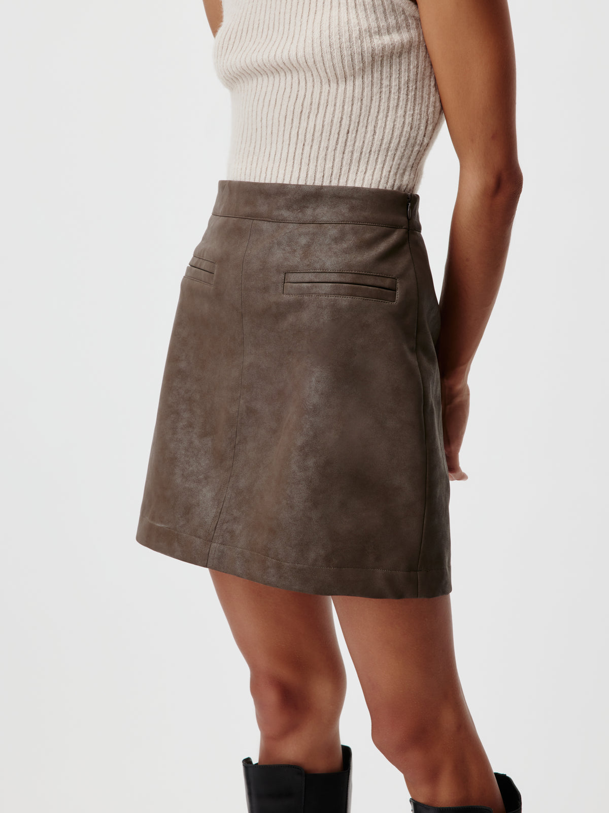 Minirock „Elisha“ von LeGer by Lena Gercke aus dunkelbraunem Kunstleder mit Gesäßtaschen, kombiniert mit einem beigen, gerippten Tanktop in modernem Design.