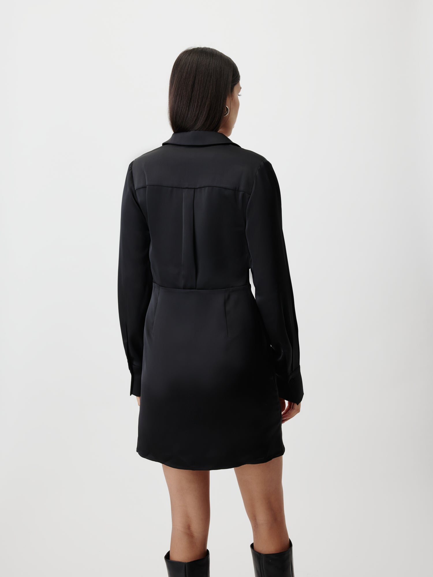 Eine Frau mit glattem, dunklem Haar steht mit dem Minikleid "Braelyn" von LeGer by Lena Gercke und schwarzen kniehohen Stiefeln vor einem schlichten weißen Hintergrund.
