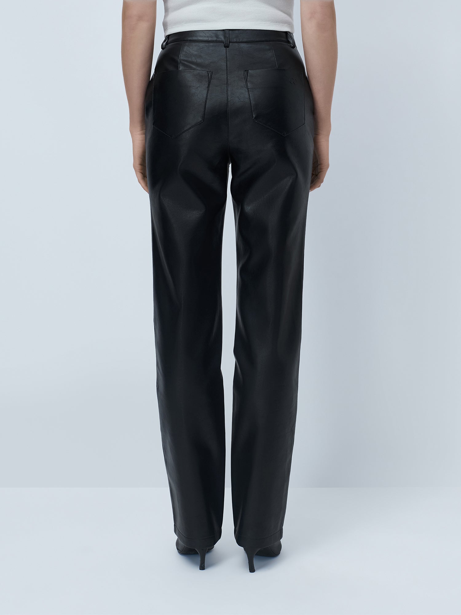 Eine Person trägt die „Insa“-Hose von LeGer by Lena Gercke mit hohem Bund und geradem Bein sowie schwarze High Heels und steht vor einem schlichten, hellgrauen Hintergrund, von hinten zu sehen.