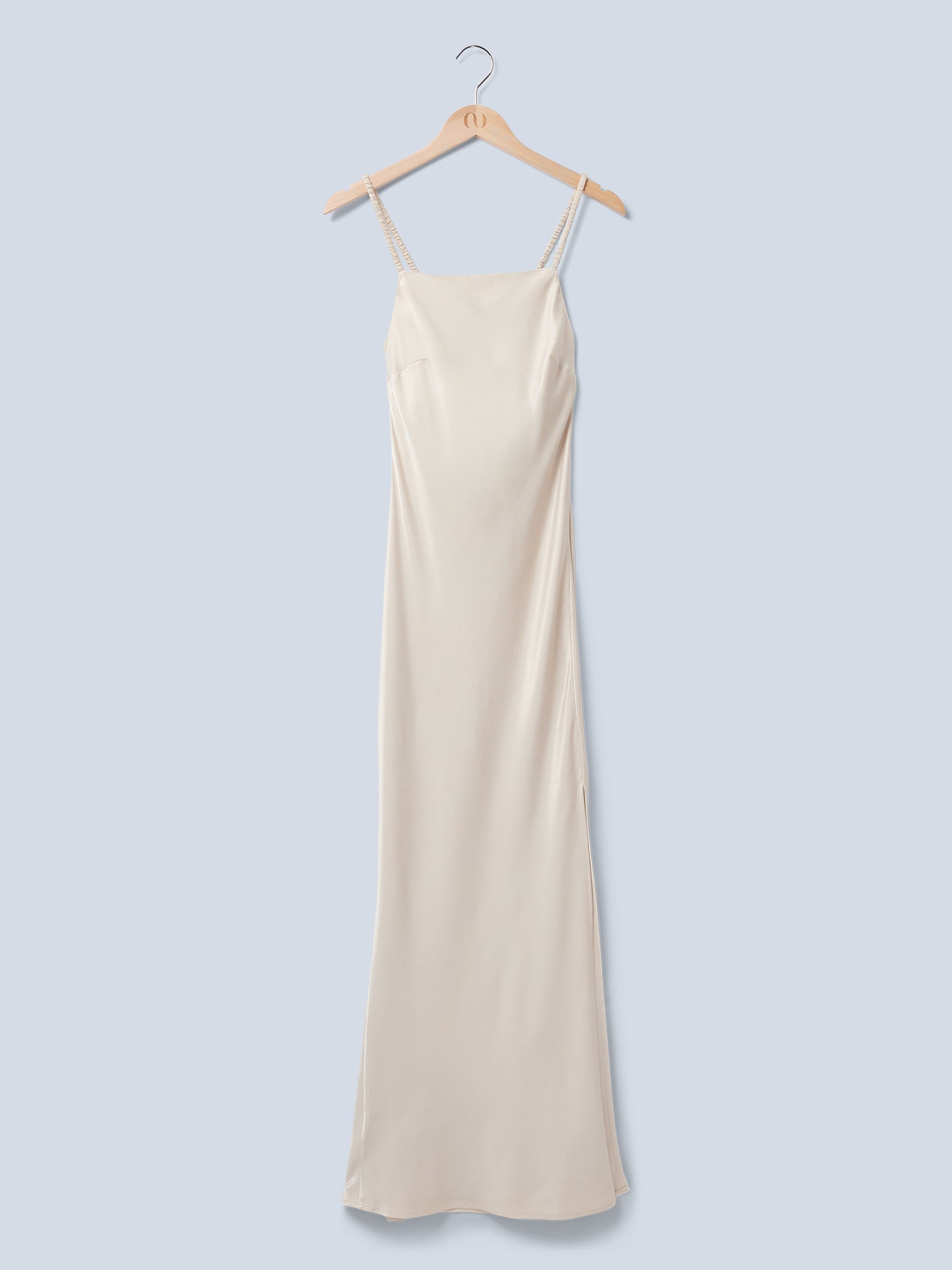 Ein langes, ärmelloses Maxikleid aus beigem Satin – das „Antonie“-Kleid von LeGer by Lena Gercke – mit geradem Ausschnitt und dünnen Trägern hängt an einem Holzkleiderbügel vor einem hellgrauen Hintergrund.