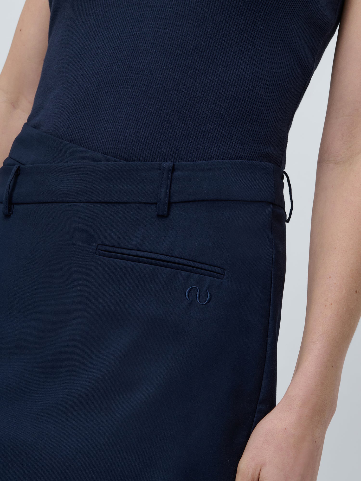 Eine Person trägt einen marineblauen LeGer by Lena Gercke Dita-Rock, Regular Fit im Mini-Länge-Stil, mit kleiner Tasche und dezentem Logo-Detail, gepaart mit einem passenden Oberteil.