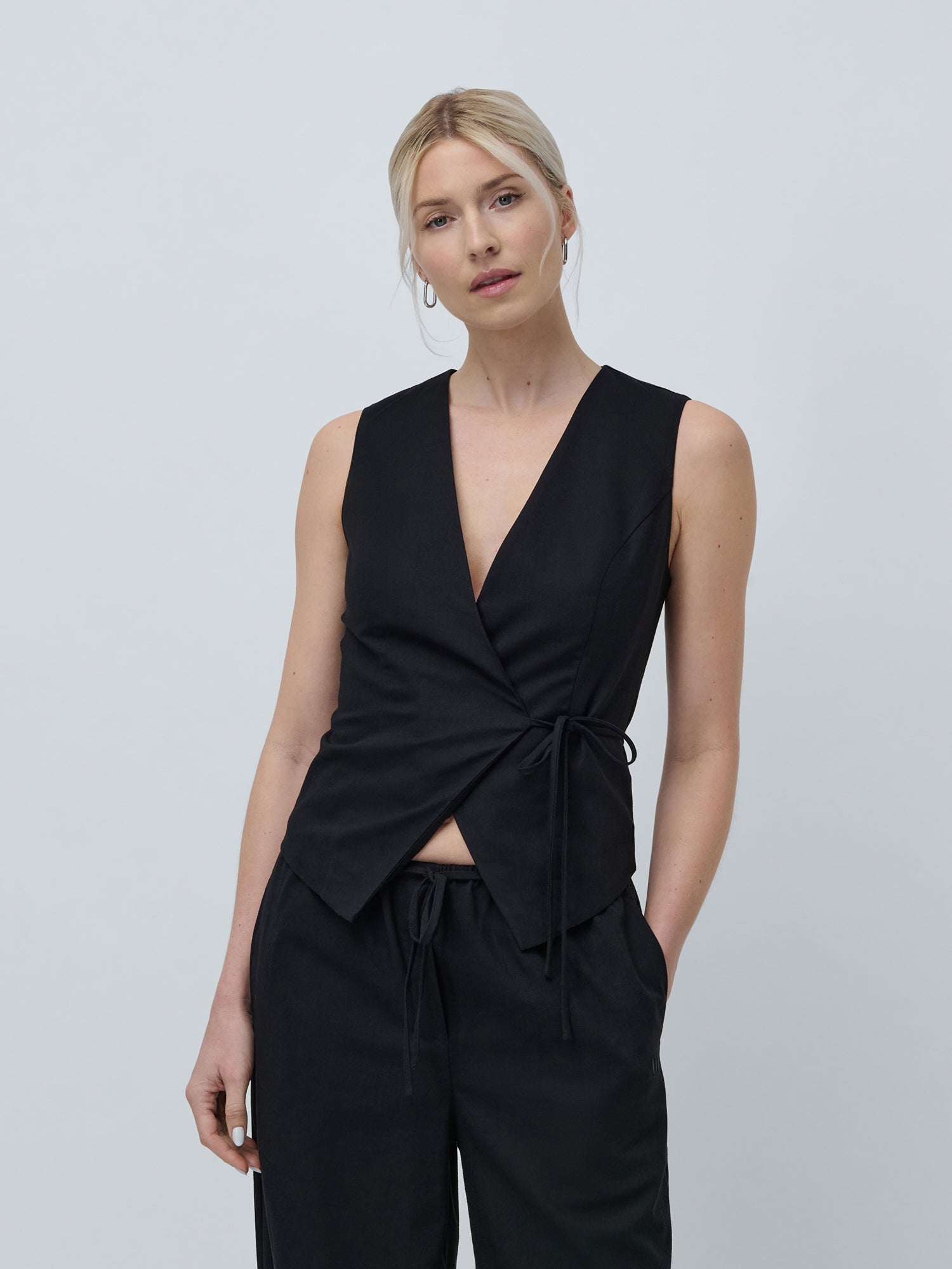 Eine Person mit heller Haut und blondem, nach hinten gestyltem Haar trägt das Emelie Set Schwarz Regular von LeGer by Lena Gercke und posiert vor einem schlichten hellgrauen Hintergrund.
