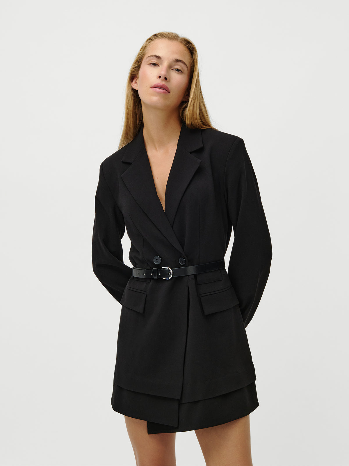 Eine Person mit langen, glatten blonden Haaren trägt das Kleid „Jeromina“ von LeGer by Lena Gercke, das sich durch eine normale Passform mit schwarzem Gürtel, Pattentaschen, einen gestuften Saum und Langarm-Ärmel auszeichnet, vor einem schlichten weißen Hintergrund.