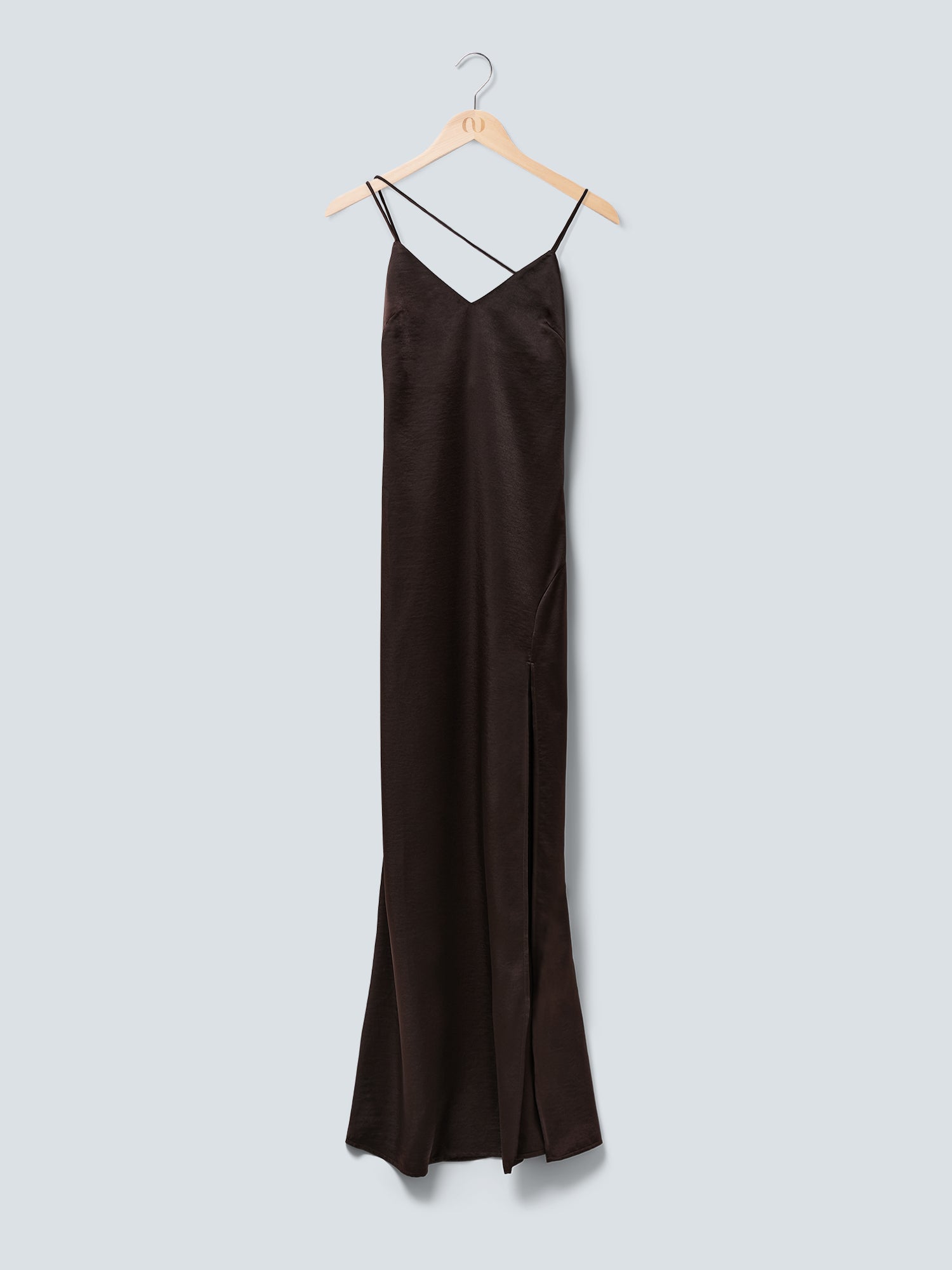 Das Kleid „Lena“ von LeGer by Lena Gercke ist ein langes, schwarzes Maxikleid aus Satin mit schmaler Passform, dünnen Spaghettiträgern – darunter ein asymmetrischer Träger – und einem Seitenschlitz am Saum. Es hängt auf einem Holzkleiderbügel vor einem hellgrauen Hintergrund.