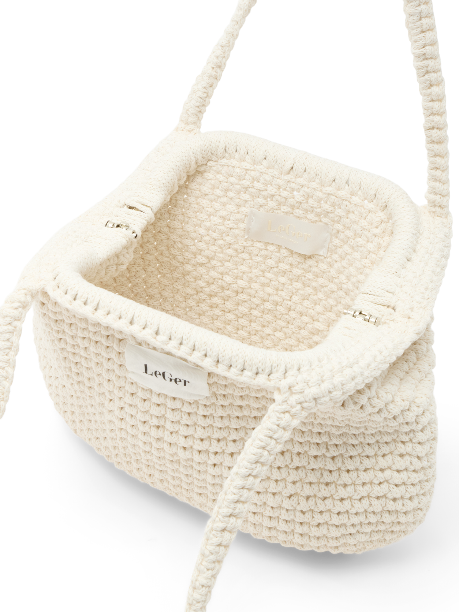 Eine Nahaufnahme der cremefarbenen „Perle Bag“ von LeGer by Lena Gercke, die mit ihrer Häkeloptik, der rechteckigen Öffnung, dem gewebten Trageriemen und dem Stoffetikett auf der Vorderseite mit der Aufschrift „LeGer“ sommerliche Leichtigkeit ausstrahlt.
