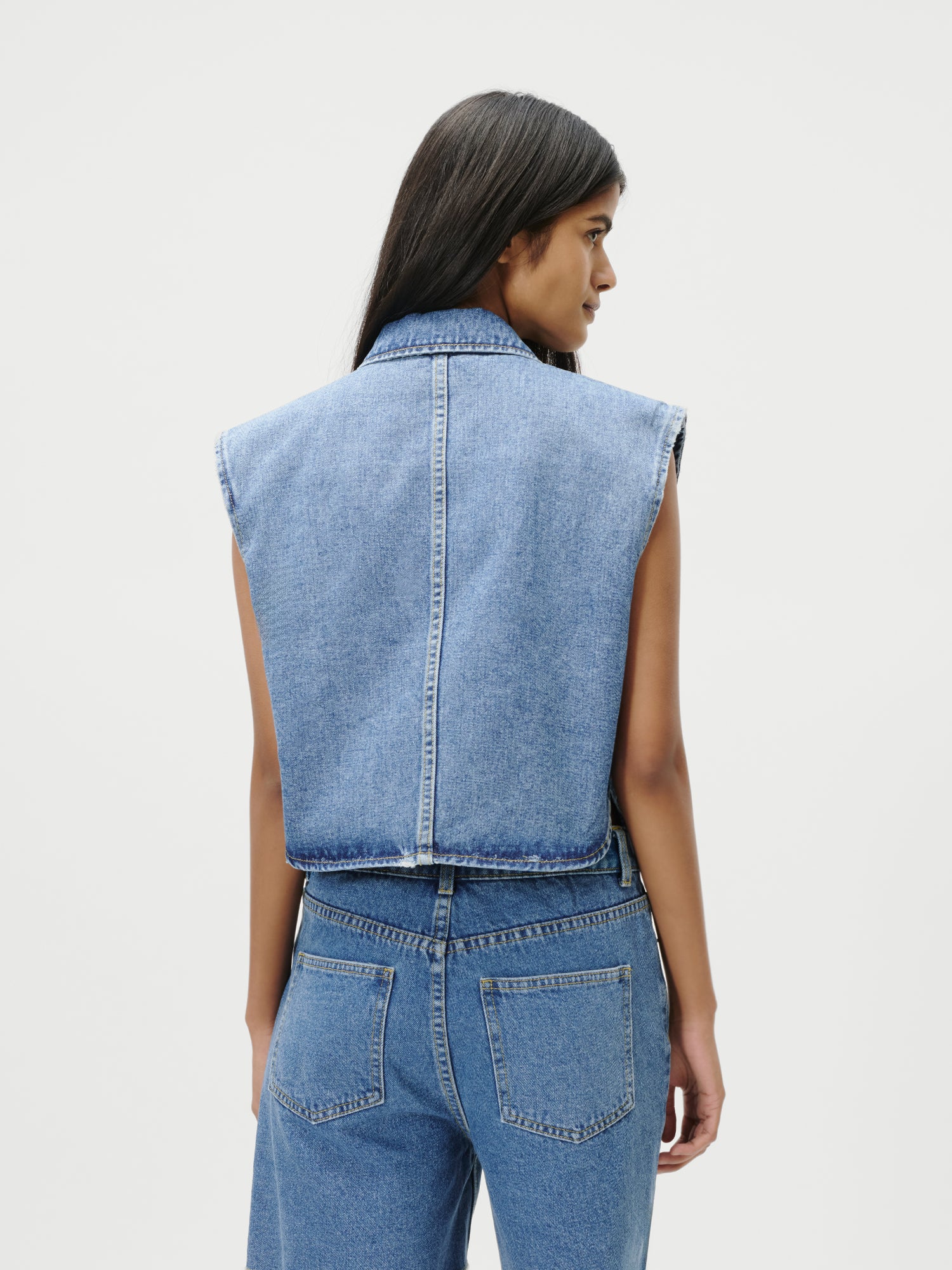 Abgebildet ist eine Person mit langen dunklen Haaren von hinten, die die LeGer by Lena Gercke Shirin Vest und eine hochgekrempelte Bluejeans in Größe 36, Passform Normal, vor einem schlichten weißen Hintergrund trägt. Das Modell ist 1,74 m groß.