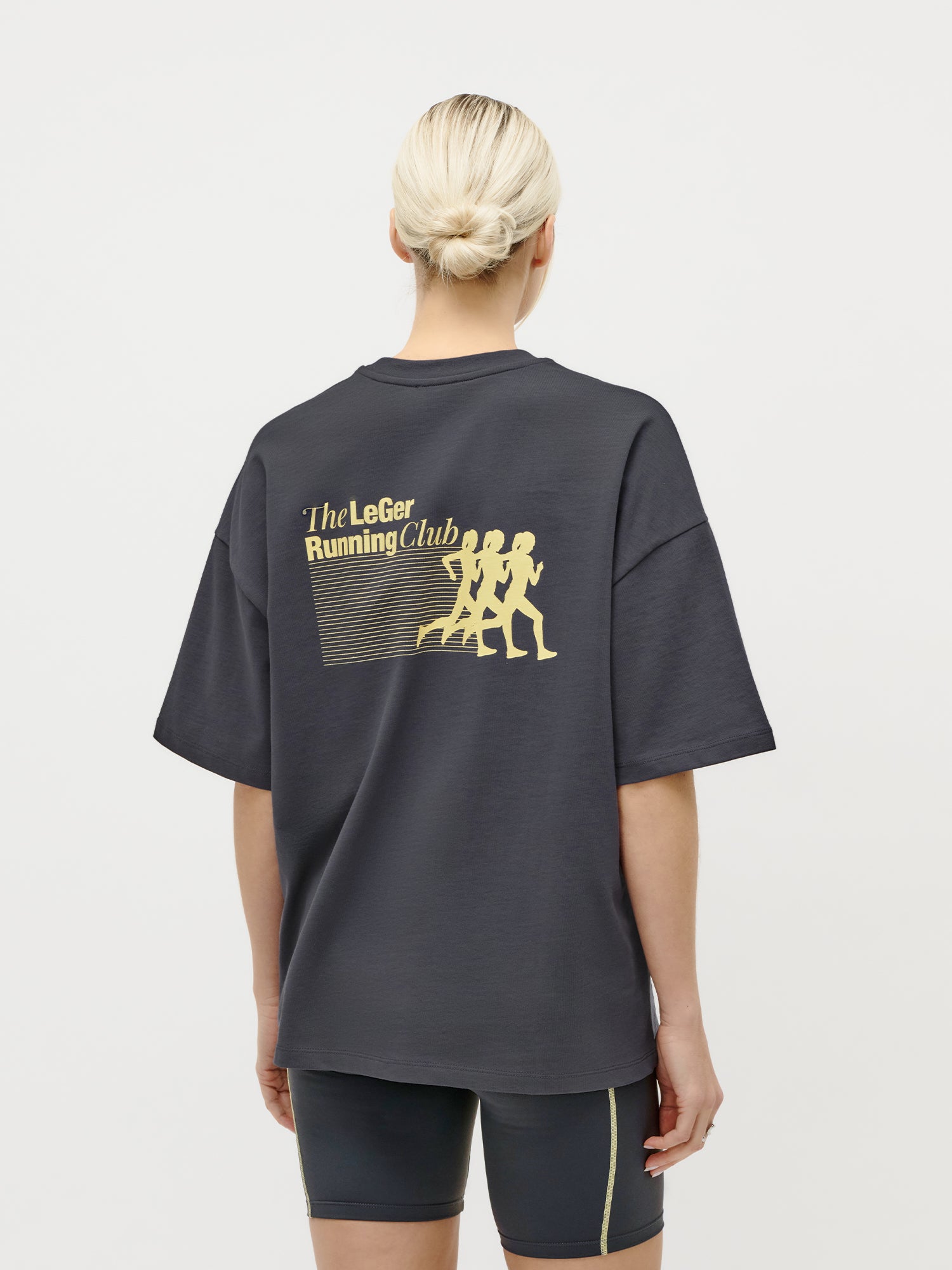 Rückansicht des übergroßen „Regina“-T-Shirts von LeGer by Lena Gercke in Dunkelgrau mit einem goldenen „LeGer Running Club“-Aufdruck, der drei Läufer zeigt – ideal für einen lässigen Streetstyle.
