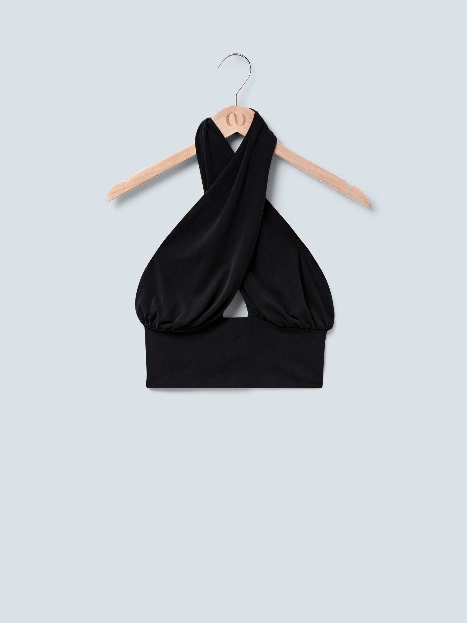 Das Agathe Top von LeGer by Lena Gercke ist ein schwarzes, ärmelloses Crossover-Crop-Top mit überkreuzter Vorderseite, das auf einem Holzbügel vor hellgrauem Hintergrund gezeigt wird.