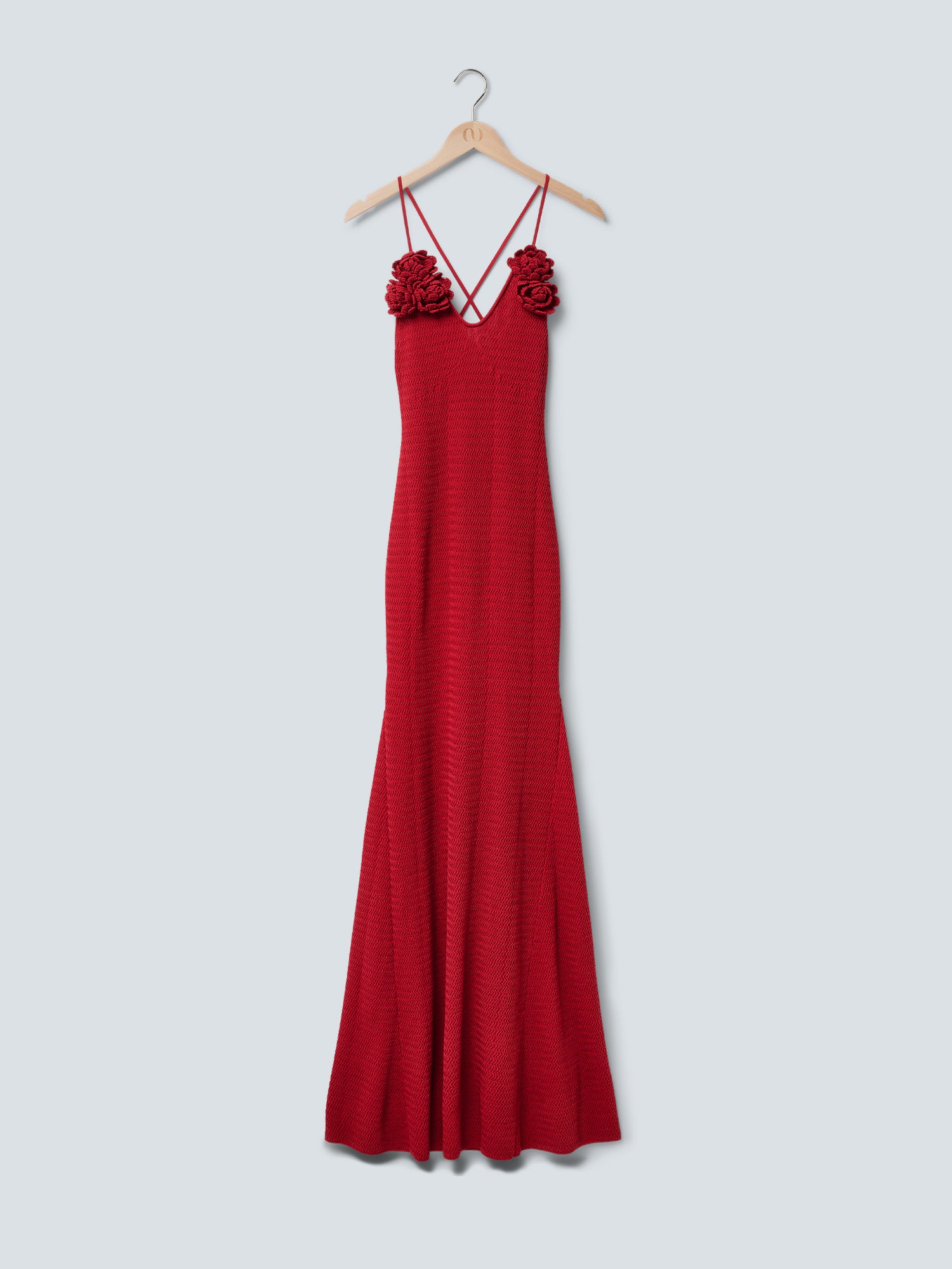 Das „Lia“-Kleid von LeGer by Lena Gercke ist ein langes, ärmelloses, rotes Maxikleid mit eng anliegendem Oberteil, dünnen, gekreuzten Trägern und floralen Verzierungen im Brustbereich, das auf einem Holzkleiderbügel vor einem hellgrauen Hintergrund präsentiert wird.