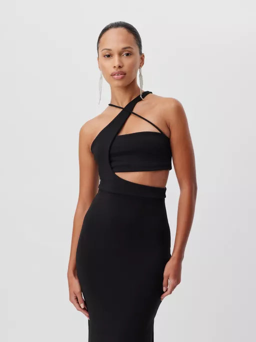 Eine Frau in einem stylischen, schwarzen One-Shoulder-Kleid mit Cut-Out-Details posiert vor einem schlichten Hintergrund. Sie trägt lange, geometrische Ohrringe und ihr Haar ist zurückgebunden.
