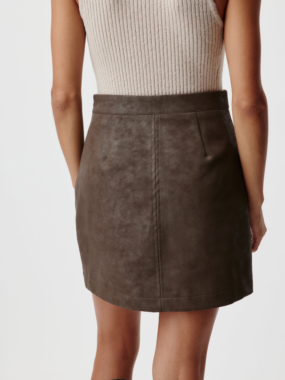 Rückansicht einer Person, die ein beiges, geripptes Tanktop und einen dunkelbraunen „Elisha“-Rock mit modernem Design trägt.