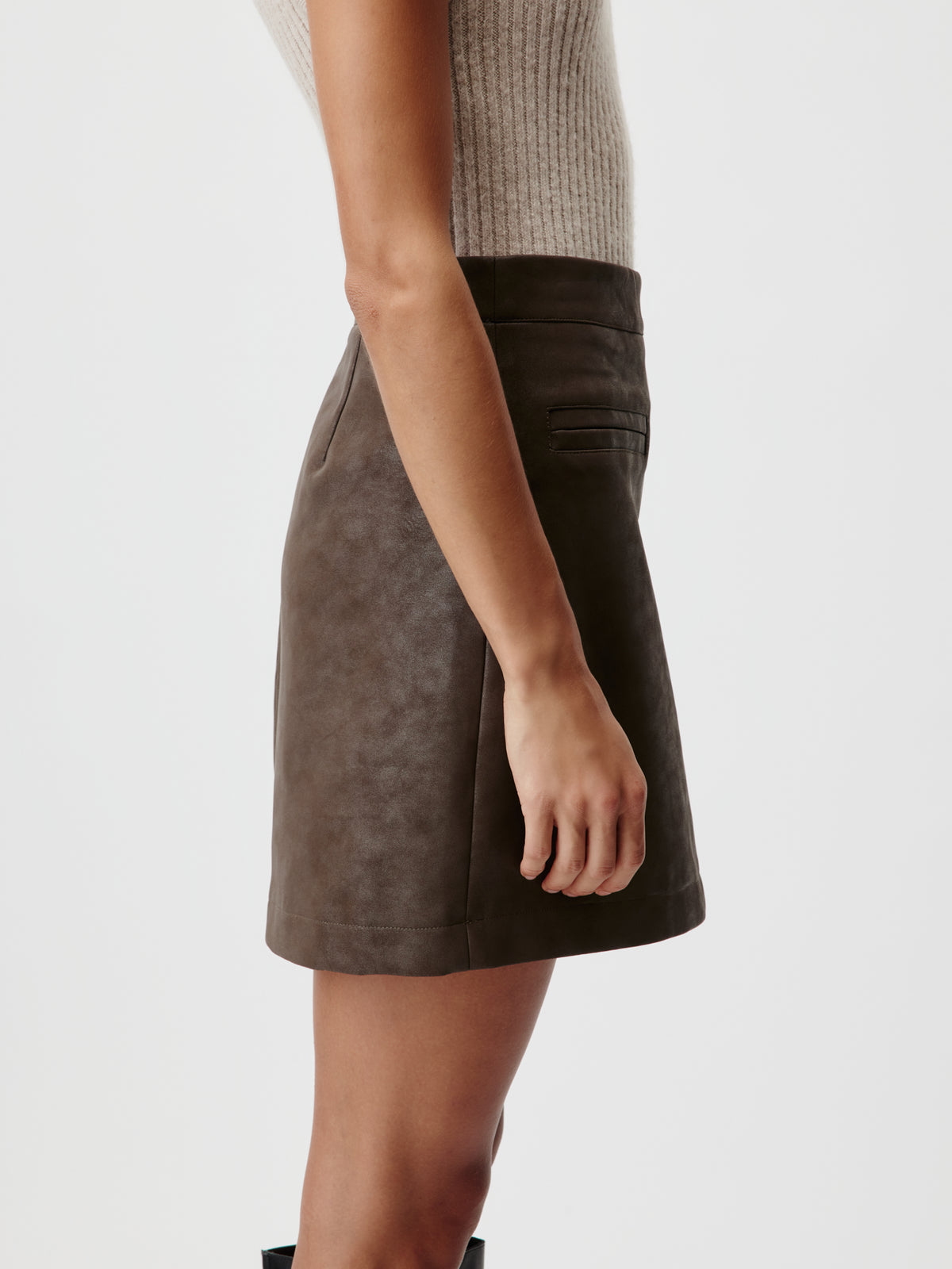 Seitenansicht einer Person, die einen dunkelbraunen „Elisha“-Rock von LeGer by Lena Gercke mit hohem Bund und einer kleinen Tasche trägt.