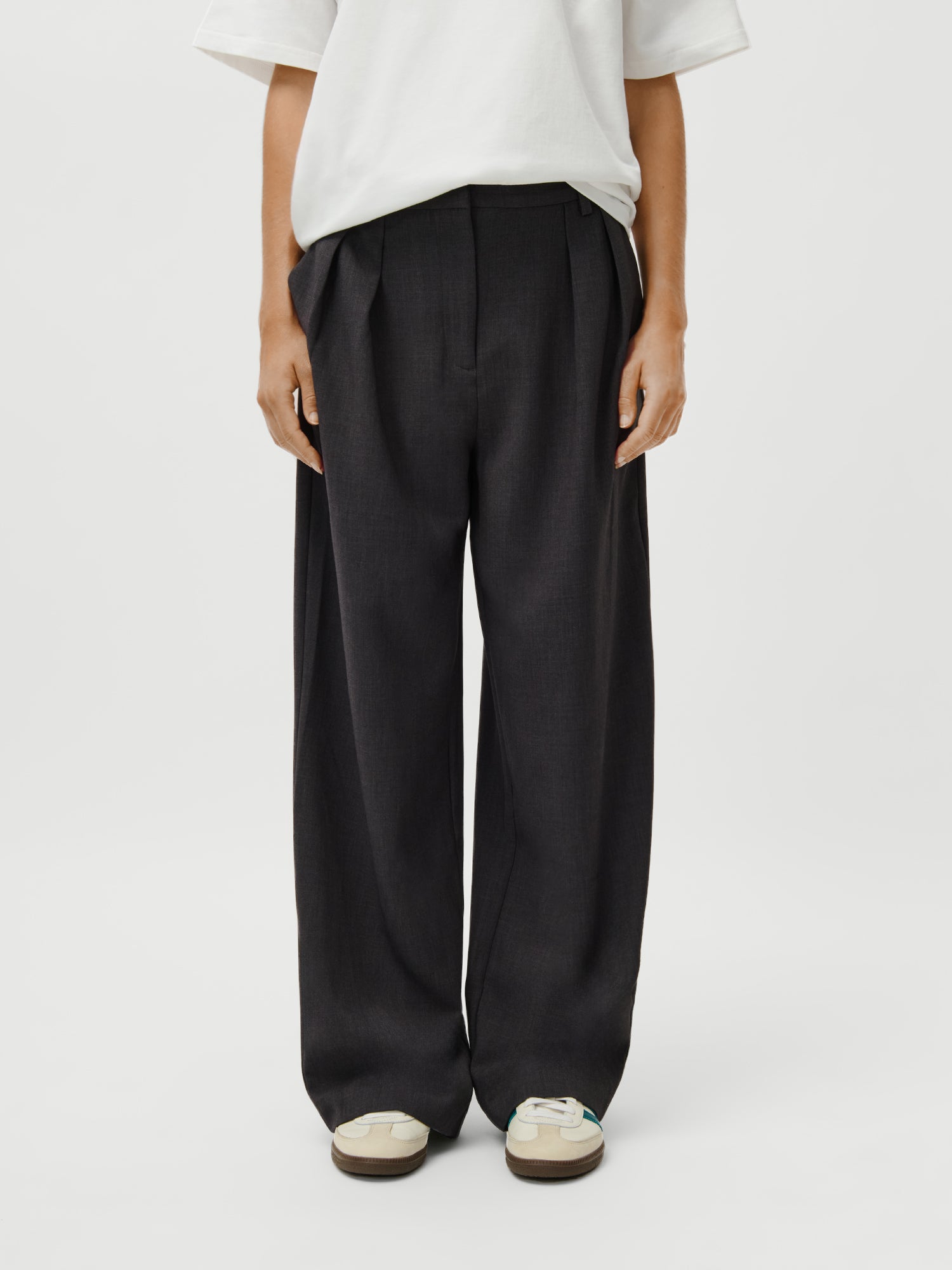 Model (1.73m) trägt Größe 36 der LeGer x Oh April - Franja Pants von LeGer by Lena Gercke, locker geschnittene, hochtaillierte schwarze Hose im Maxi-Stil. Nur die untere Körperhälfte ist sichtbar; Arme entspannt an den Seiten.