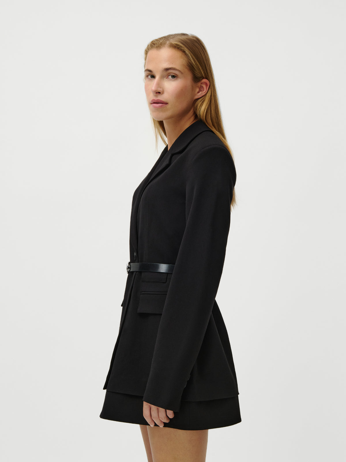 Eine Person mit langen, glatten Haaren trägt das Kleid „Jeromina“ von LeGer by Lena Gercke und steht seitlich vor einem schlichten weißen Hintergrund.