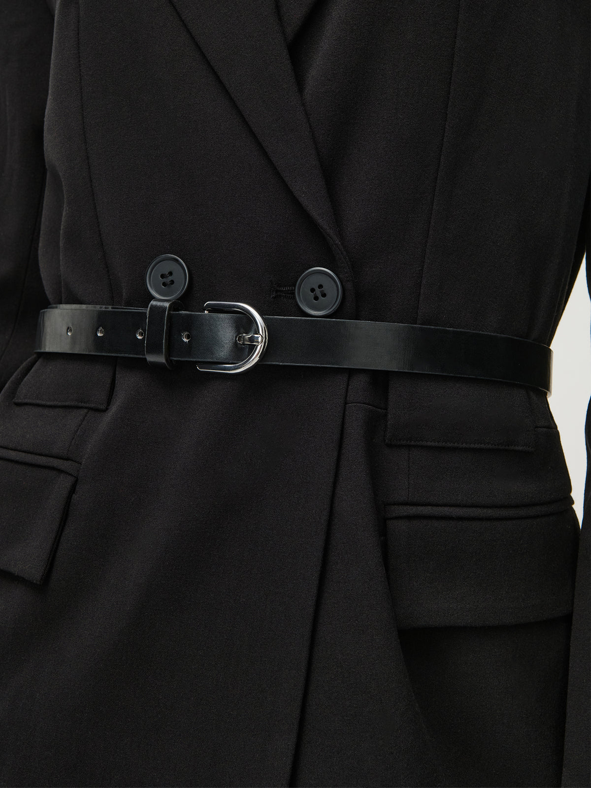 Eine Nahaufnahme einer Person, die das Kleid „Jeromina“ von LeGer by Lena Gercke trägt. Das Kleid besticht durch einen schwarzen, taillierten Schnitt in normaler Passform mit schwarzen Knöpfen und einem schmalen schwarzen Ledergürtel mit silberner Schnalle an der Taille. Die langen Ärmel (Langarm) verleihen dem Kleid einen eleganten Touch.