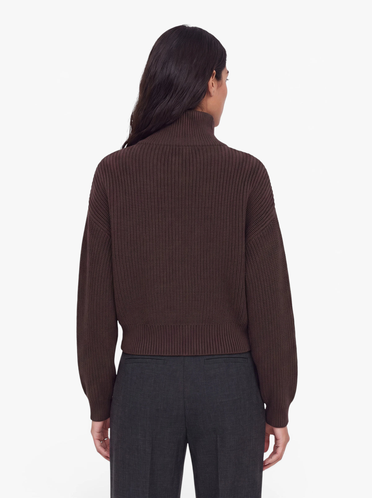 Eine Person mit langen dunklen Haaren, die den Pullover „Cindy“ von LeGer by Lena Gercke trägt – einen dunkelbraunen Rippstrickpullover mit Reißverschluss – sowie eine dunkelgraue Hose, steht mit dem Rücken zur Kamera vor einem schlichten weißen Hintergrund.