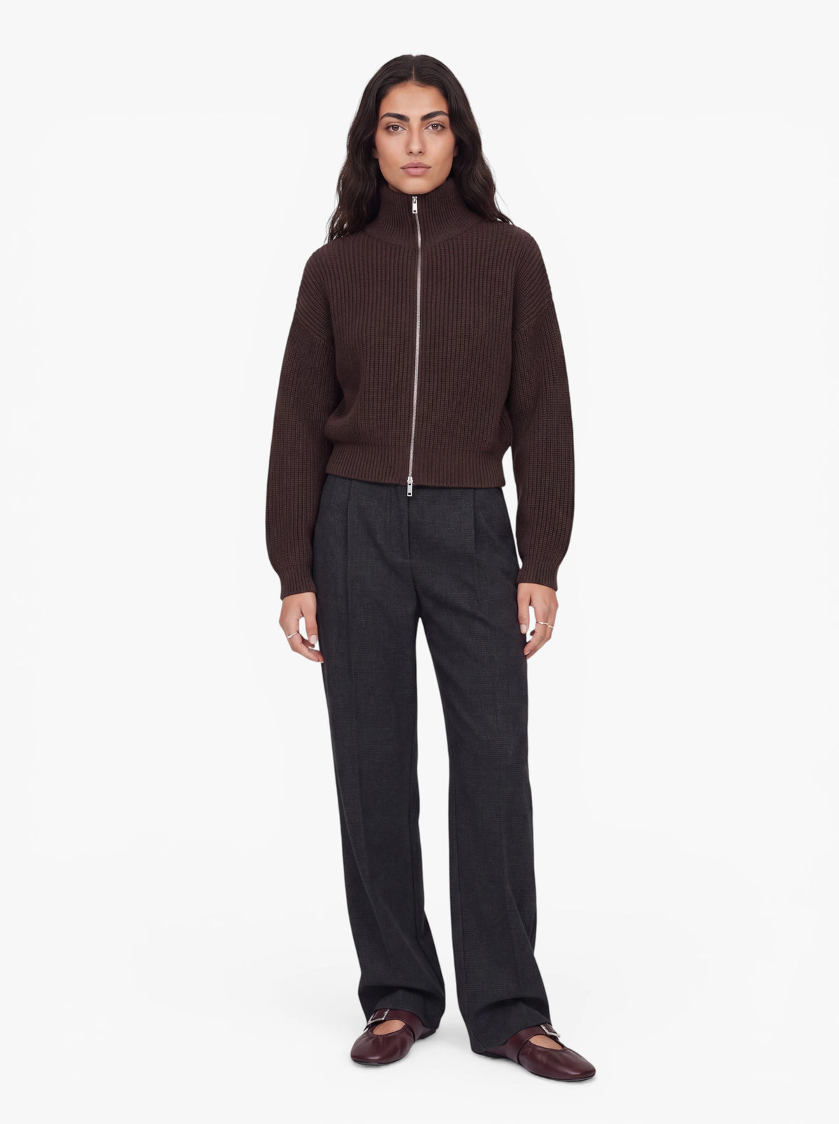 Eine Person steht vor einem weißen Hintergrund und trägt den dunkelbraunen Pullover „Cindy“ von LeGer by Lena Gercke, dazu eine dunkelgraue Hose und dunkelbraune Schuhe. Sie hat langes dunkles Haar und einen neutralen Gesichtsausdruck.