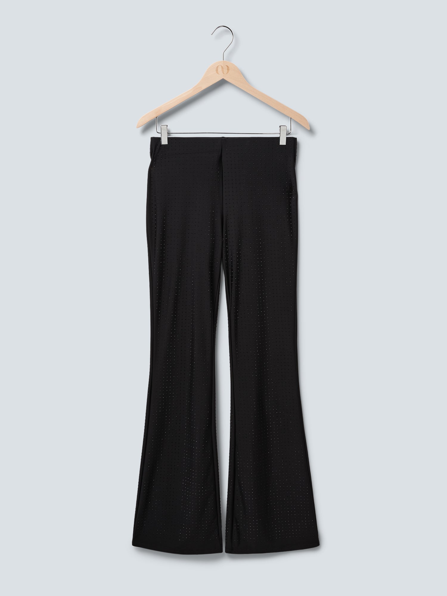 Die Daniela Pants von LeGer by Lena Gercke ist eine schwarze, ausgestellte Hose in normaler Passform mit dezenter Pünktchenstruktur und elastischem Pull-on-Design, die auf einem Holzbügel vor hellgrauem Hintergrund präsentiert wird.