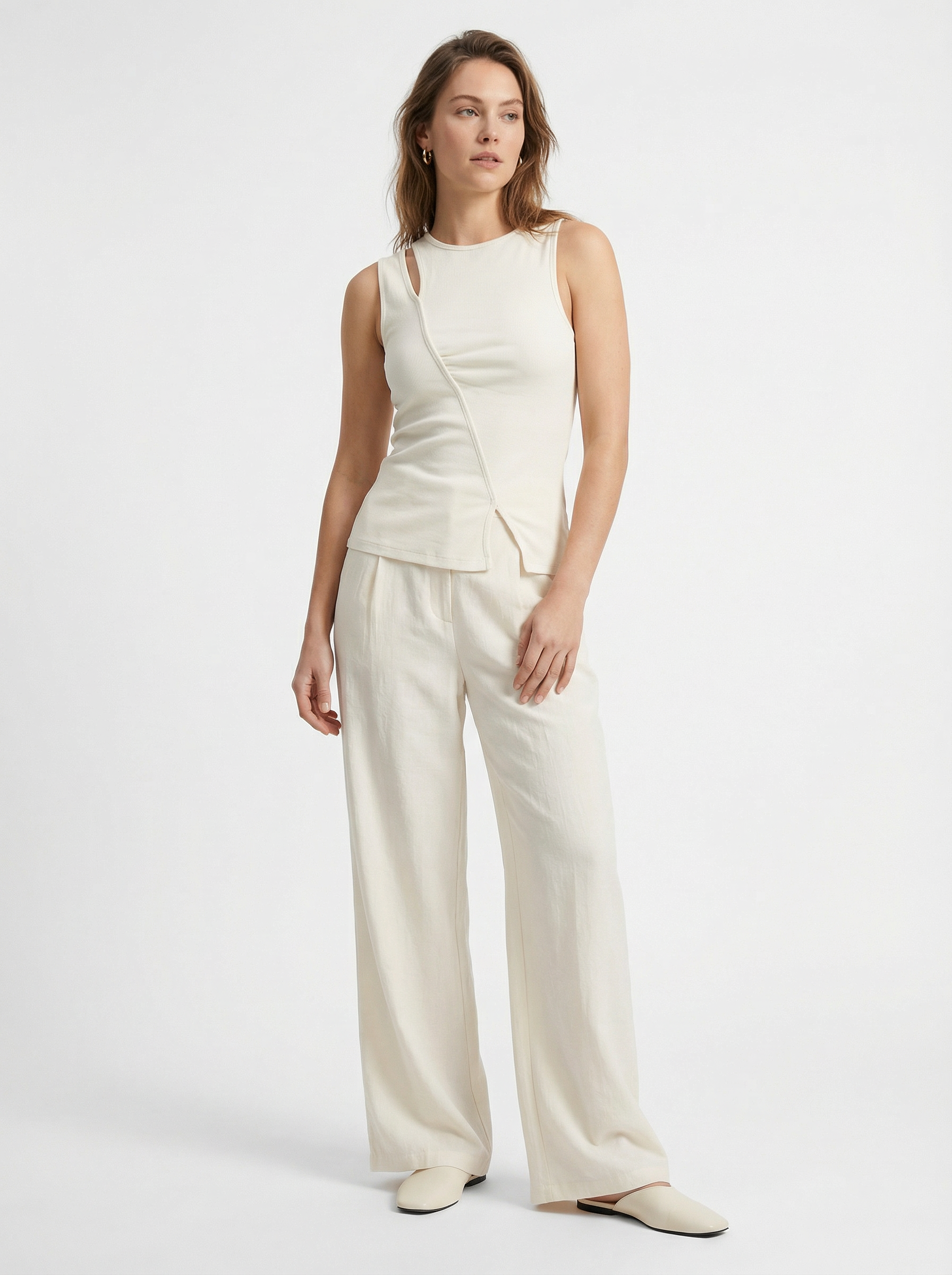 Eine Frau mit hellbraunem Haar trägt eine cremefarbene Thorina-Hose von LeGer by Lena Gercke, gepaart mit einem passenden ärmellosen Oberteil und cremefarbenen Schuhen vor einem schlichten weißen Hintergrund, und zeigt damit einen modernen, von Maxis inspirierten Stil.