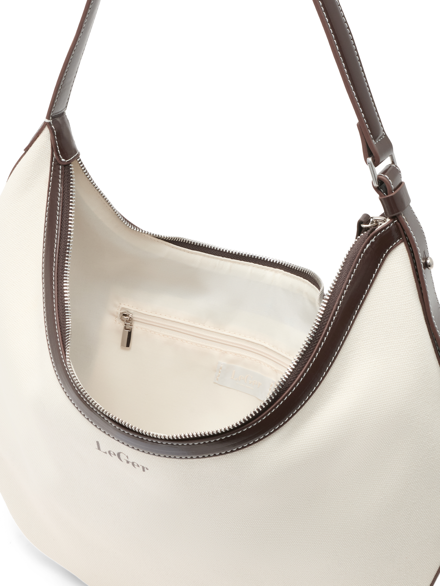 Eine Nahaufnahme der cremefarbenen „Gisa Bag“ von LeGer by Lena Gercke in Halbmondform, mit braunen Henkeln und Besätzen, einem teilweise geöffneten Reißverschluss, der den Blick auf eine Innentasche mit Reißverschluss und Stoffetikett freigibt – ein elegantes Accessoire für jeden Anlass.