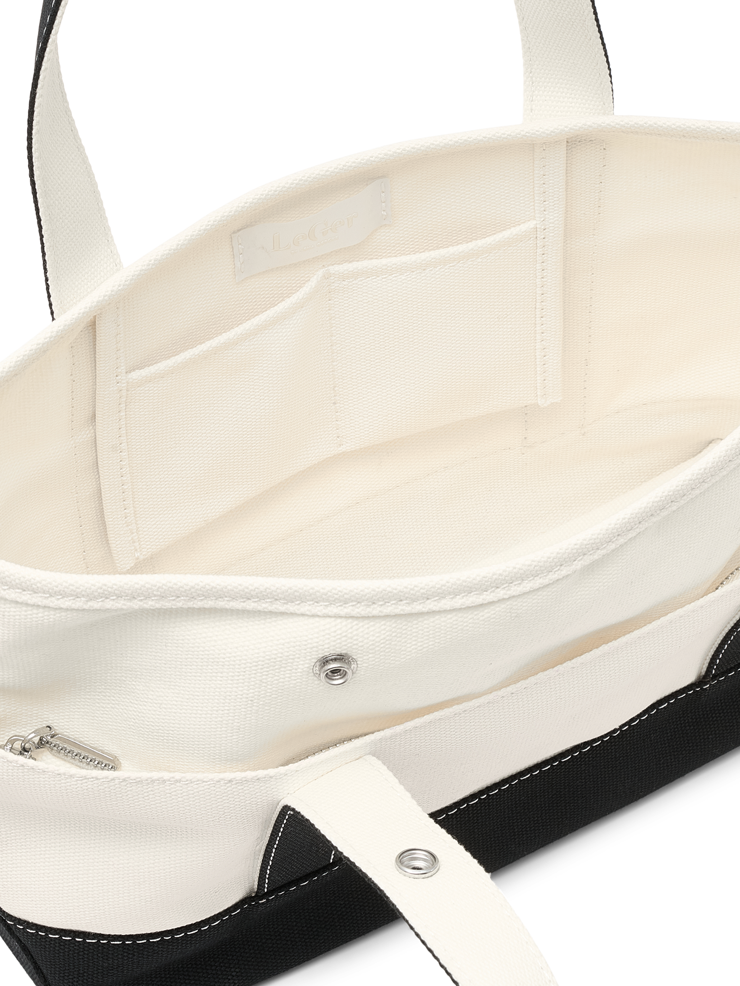 Die Sheila Bag von LeGer by Lena Gercke ist eine offene Tasche aus weißem Segeltuch mit schwarzem Rand. Sie verfügt über Innenfächer: ein kleines Reißverschlussfach, zwei offene Fächer und einen Druckknopfverschluss.