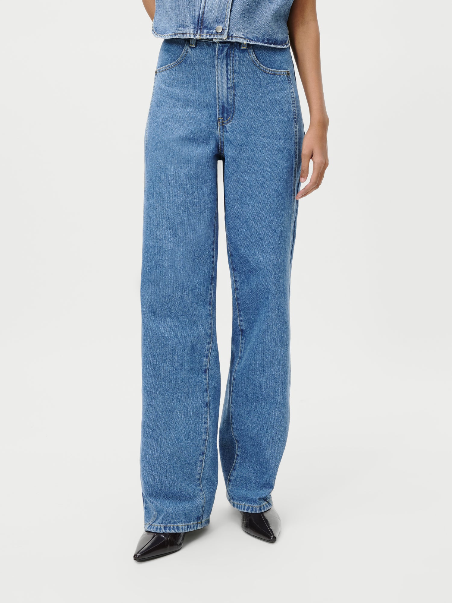 Eine Person, die Shirin Pants von LeGer by Lena Gercke in Größe 36 trägt, gepaart mit schwarzen spitzen Schuhen, steht mit den Händen an der Seite, von den Schultern abwärts vor einem schlichten weißen Hintergrund.