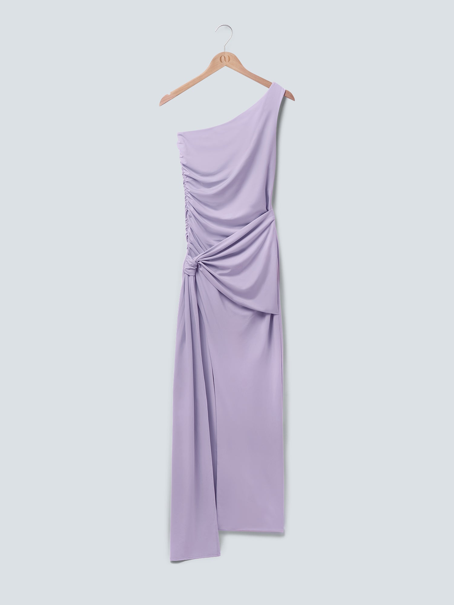 Ein hellviolettes „Claire“-Kleid von LeGer by Lena Gercke mit einer asymmetrischen Ein-Schulter-Silhouette, gerafften Details und einem gerafften Knoten an der Taille hängt auf einem Holzkleiderbügel vor einem hellen Hintergrund.