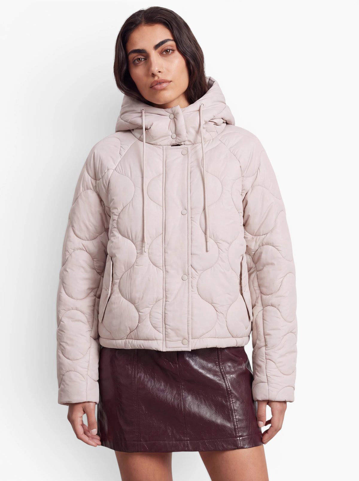 Eine Person trägt die Jacke „Fray“ von LeGer by Lena Gercke in Hellbeige mit Oversize-Schnitt und Kapuze, dazu einen dunkelbraunen Lederminirock, und steht vor einem schlichten weißen Hintergrund.