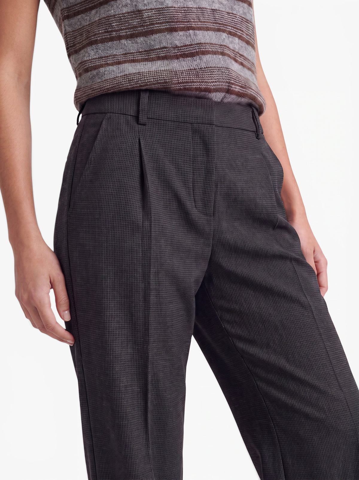 Eine Person trägt die Hose „Julie“ von LeGer by Lena Gercke in Dunkelgrau mit hoher Taille und dezentem Karomuster, dazu ein ärmelloses, gestreiftes Strickoberteil. Vor einem einfarbigen Hintergrund sind nur der untere Rumpf und die Oberschenkel zu sehen.