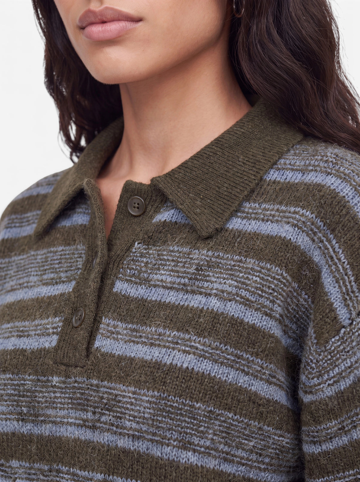 Eine Frau, die den Pullover „Delia“ von LeGer by Lena Gercke trägt – einen flauschigen, olivgrün-grau gestreiften Pullover mit Hemdkragen und Knöpfen –, wird vor einem einfarbigen Hintergrund von den Schultern aufwärts gezeigt.