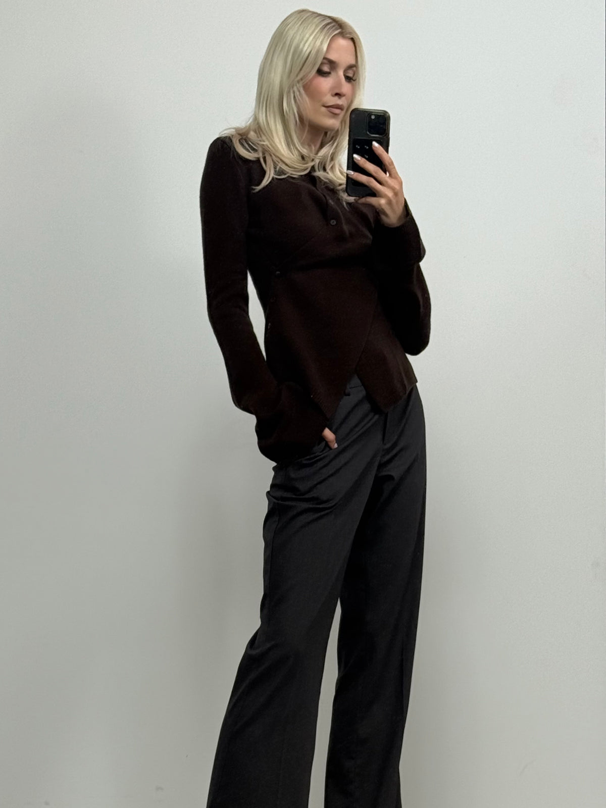 Eine Person mit langen blonden Haaren trägt eine dunkle Jacke und die Hose „Fergie“ Tall von LeGer by Lena Gercke. Sie steht vor einem schlichten hellen Hintergrund und macht mit einem Smartphone ein Spiegel-Selfie.