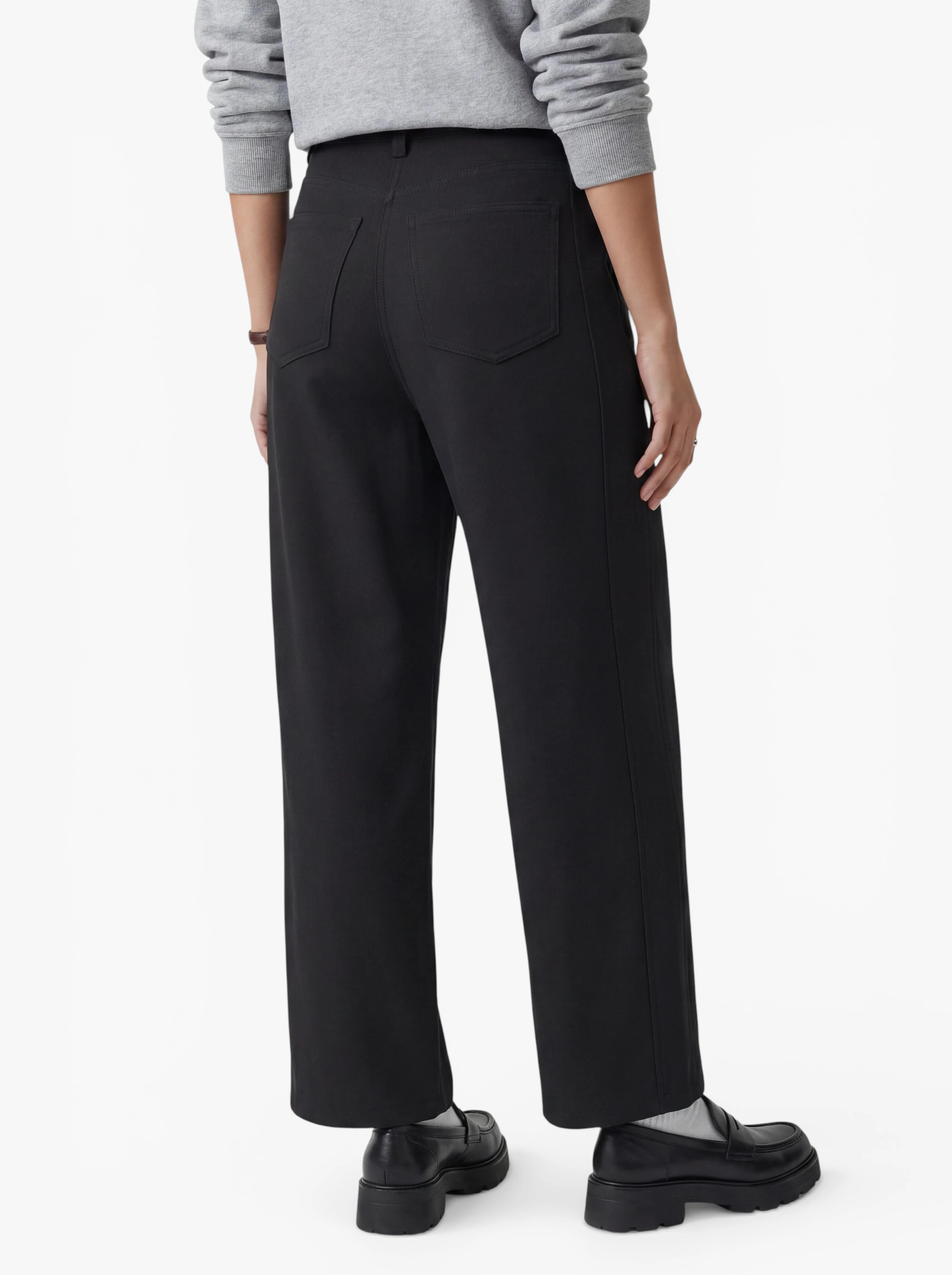 Eine Person ist von hinten zu sehen. Sie trägt die Hose „Kasha“ von LeGer by Lena Gercke – ein modernes, tailliertes Modell mit weitem Bein – in Schwarz, dazu schwarze Schuhe und ein hellgraues Langarm-Oberteil, und steht vor einem schlichten weißen Hintergrund.